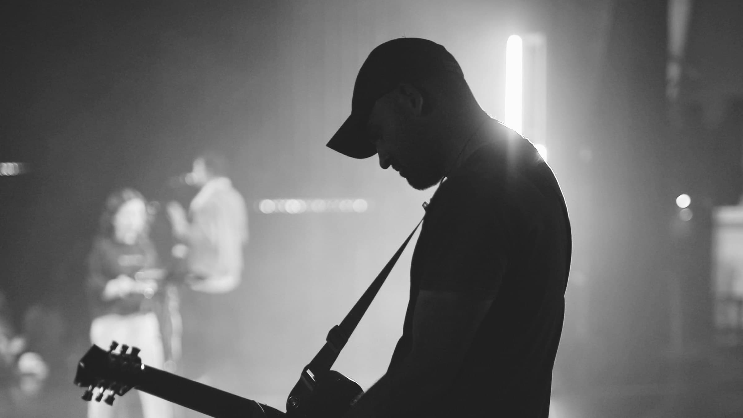 A musician with a guitar on a dim stage, ready to play.